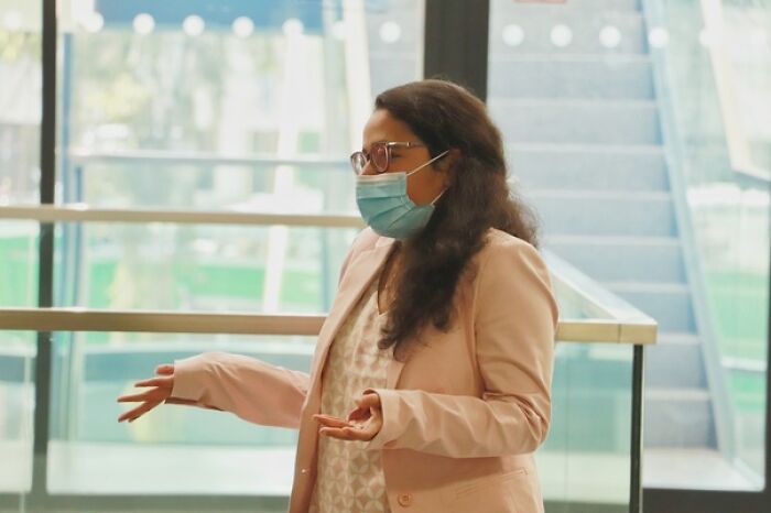 A woman in a mask and glasses talks indoors, illustrating job assumptions and stereotypes.