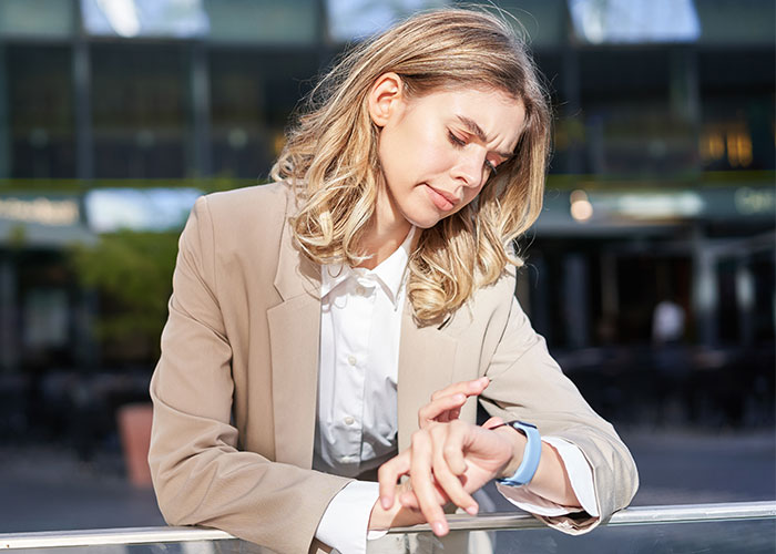 Woman looking at her watch, appearing stressed about time, outdoors in business attire. Woman looking at her watch, appearing stressed about time, outdoors in business attire.