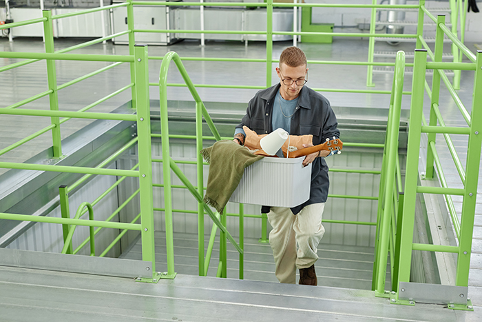 Man carrying items up stairs, planning a lesson in toxic girlfriend revenge, wearing glasses and a jacket.