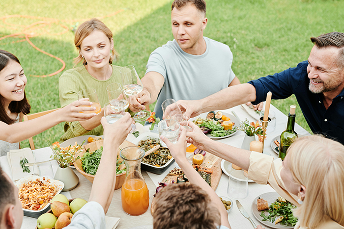 Family gathering at an outdoor table, toasting drinks. Family gathering at an outdoor table, toasting drinks.