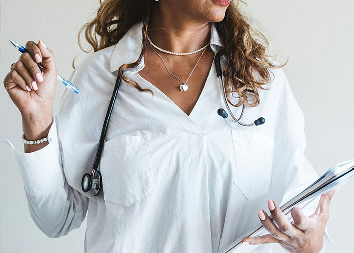 A woman in a white coat holding a clipboard and pen, representing empowerment and readiness.
