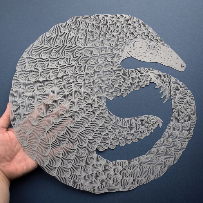 Intricate paper art design of a pangolin on a gray background, highlighting nature-inspired craftsmanship.