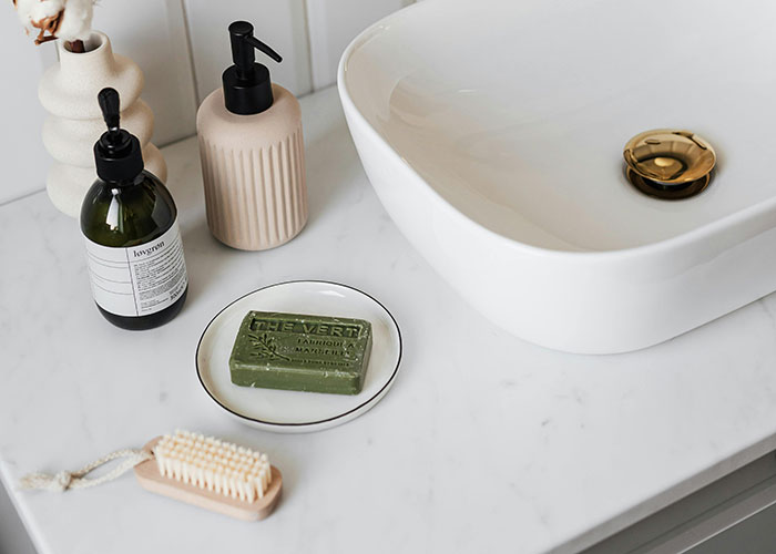 Bathroom counter with soap, lotion, a brush, and a modern sink, highlighting issues related to being overweight.