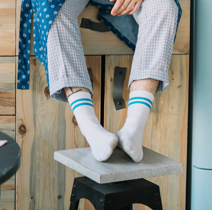 Person in white socks with blue stripes and plaid pants, sitting casually, highlighting non-physical qualities of comfort.