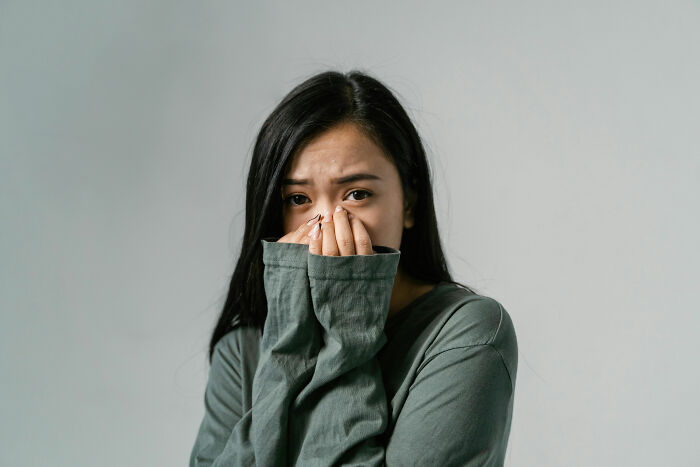 A woman in a green sweater covering her face, symbolizing a change in mindsets.