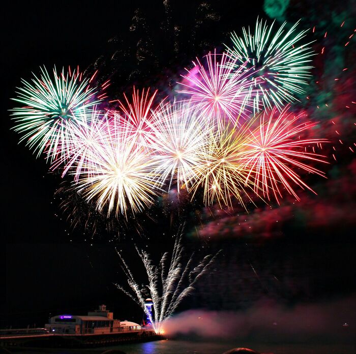 Colorful fireworks exploding in the night sky over a pier, illustrating vanished pop culture moments.