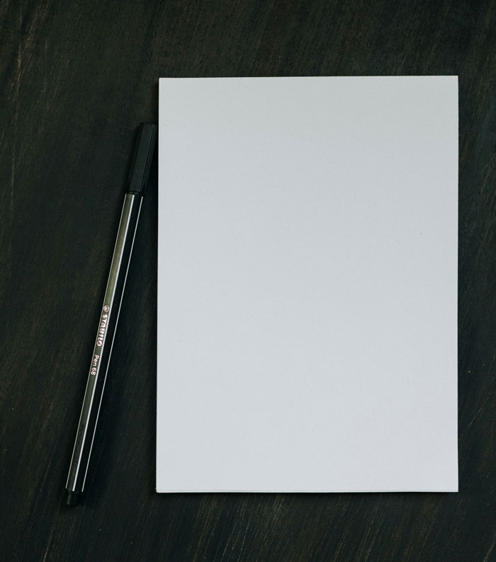 "Cuaderno y bolígrafo sobre una mesa, listos para que estudiantes escriban frases graciosas."