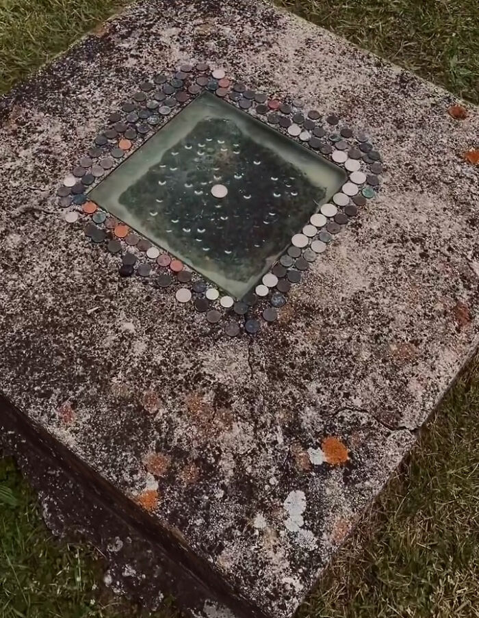 Old stone slab with coins around a glass center, showcasing fascinating world facts.