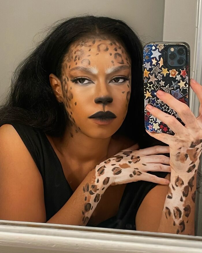Woman transforms vitiligo into artistic leopard body art, photographed in a mirror selfie for self-acceptance.
