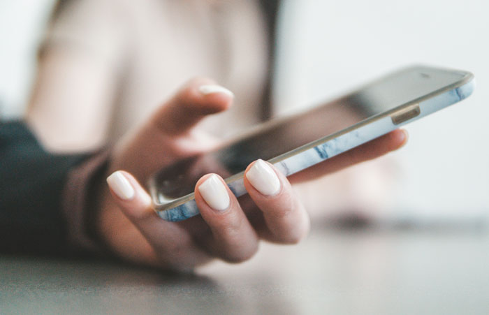 Person holding a smartphone, possibly researching a man's background for surprising discoveries.