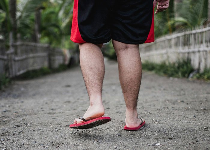 Person walking on a dirt path wearing red and black shorts, illustrating challenges about being overweight.