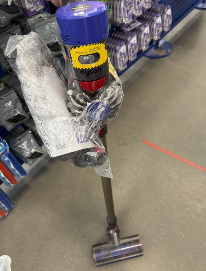 A Dyson vacuum cleaner found while thrifting, partially wrapped in plastic in a store aisle.