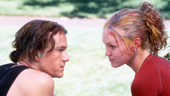 Two young people with colorful paint in a 90s scene, outdoors.