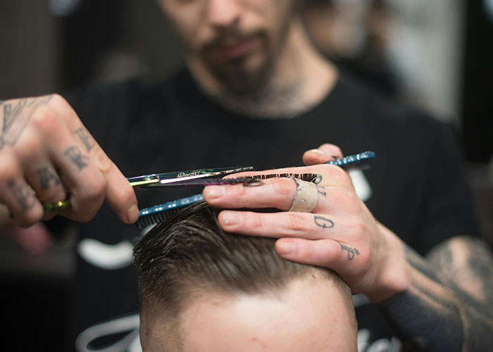 Barber with tattoos cutting hair, illustrating European culture shocks for Americans.