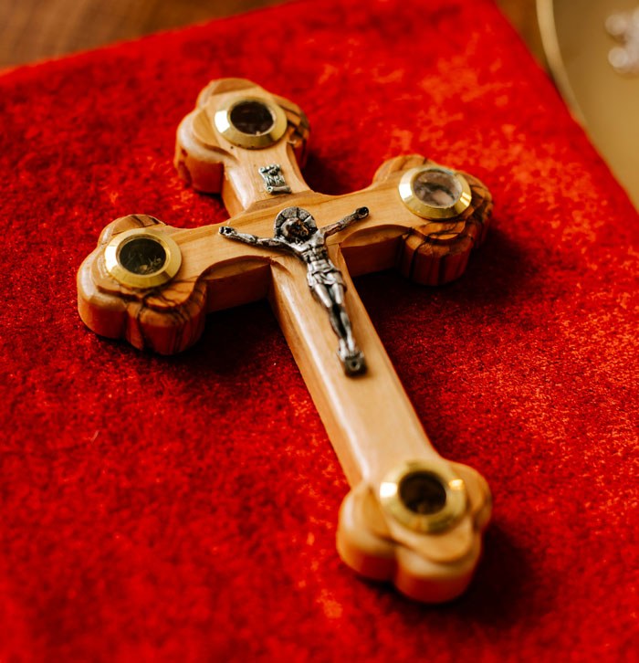 Wooden cross with a metal figure on a red textured background, related to hilarious student comments from teachers.