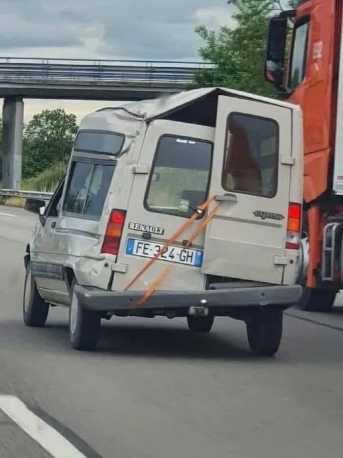 Coche en carretera con puerta trasera sostenida por cinta, una de las imágenes más raras.