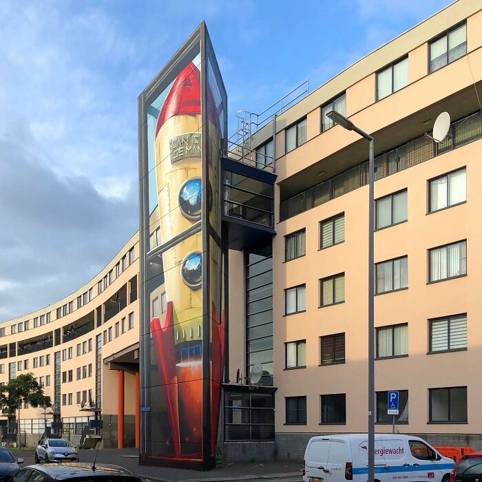 Hyperrealistic mural by Jan Is De Man featuring a rocket illusion on a city building wall.