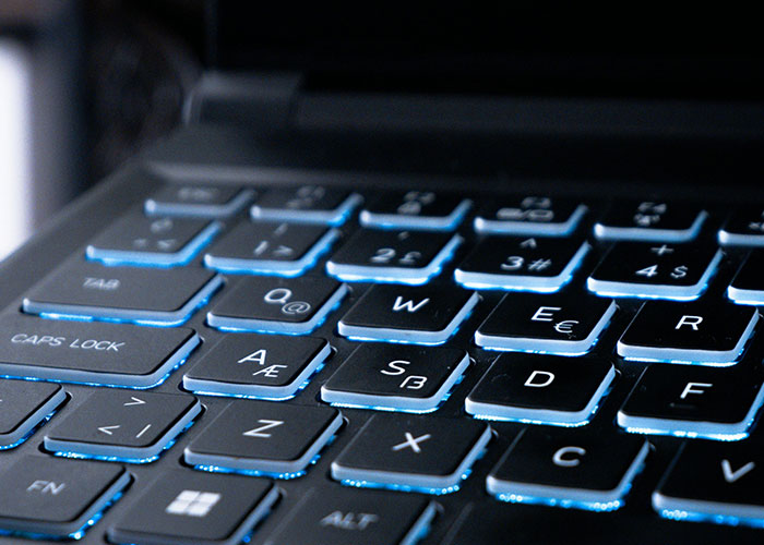 Close-up of a laptop keyboard with illuminated keys, highlighting the importance of careful actions in digital settings.