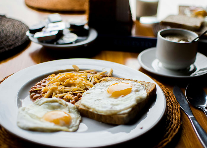 Breakfast plate with fried eggs, beans, cheese, toast, and coffee; a European dining experience.