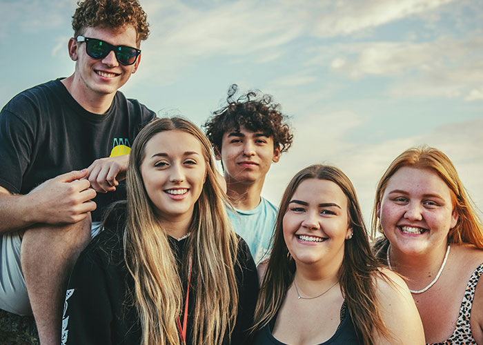 A group of five people smiling outdoors, highlighting diverse perspectives on being overweight.