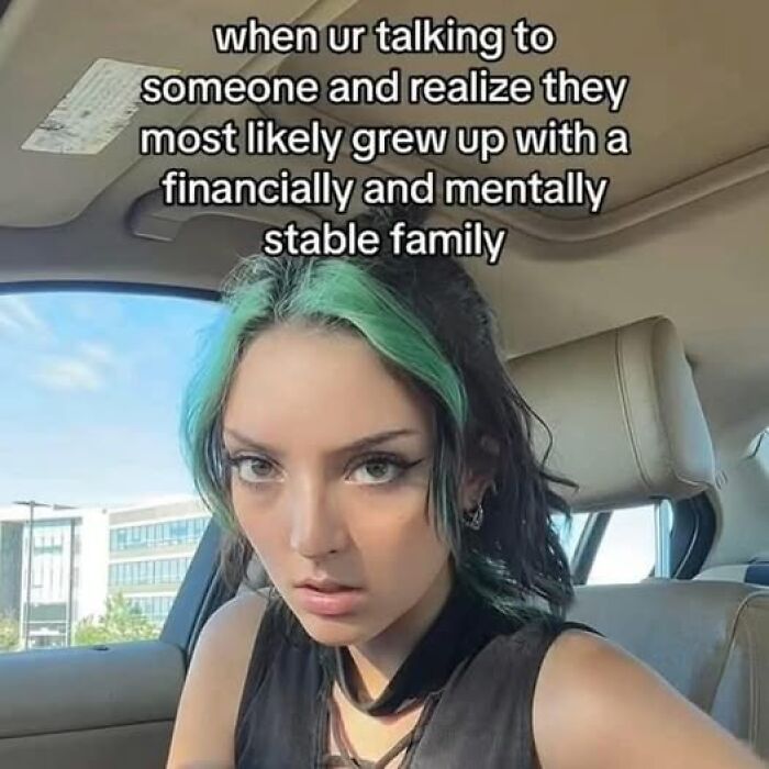 Woman with green hair in car, reacting humorously to text about growing up in a mentally stable family. Mental health meme.