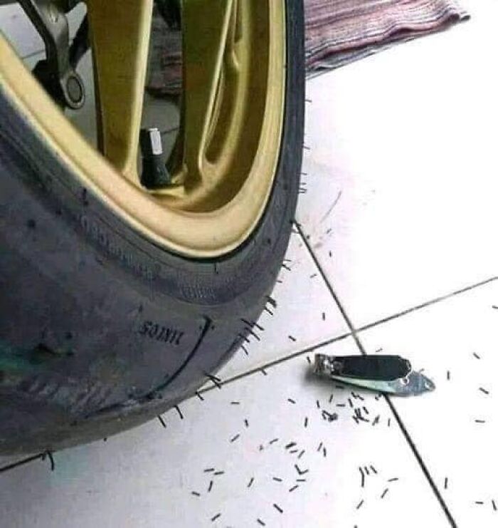 Weird image of a tire next to a nail clipper and scattered nail clippings on the floor.