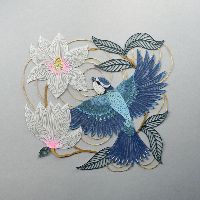 Intricate paper art design featuring a blue bird in flight with floral and leaf motifs.