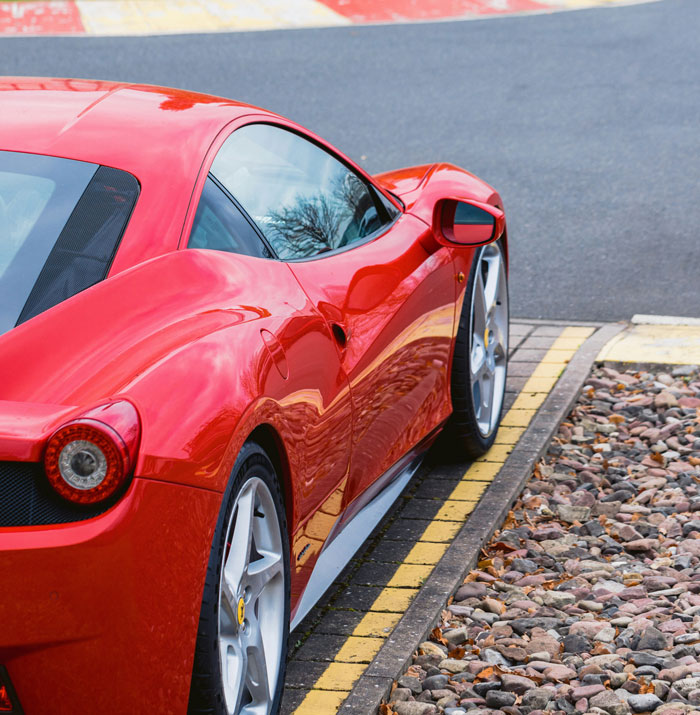 Luxury red sports car parked on a roadside, symbolizing affluent lifestyle and disconnect from reality.
