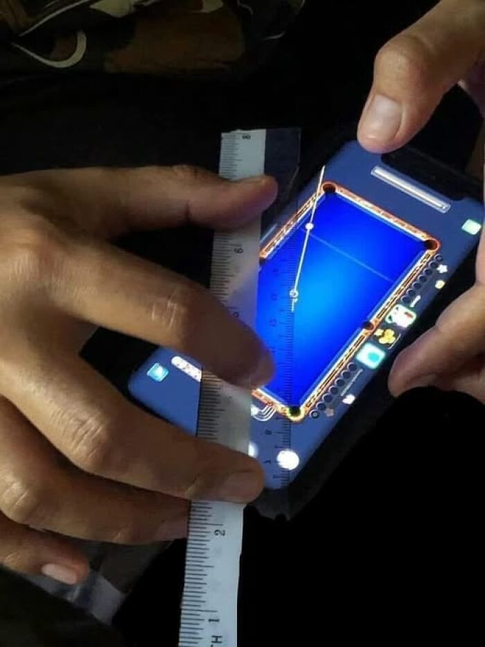 "Measuring a smartphone pool game with a ruler, capturing a weird image scenario."