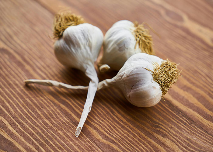 Three garlic bulbs on a wooden surface, illustrating themes of revenge and careful actions.
