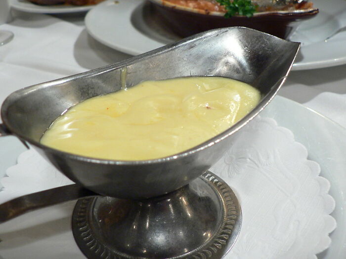 Creamy sauce in a gravy boat on a white table setting, showcasing a home chef's cooking cheat.