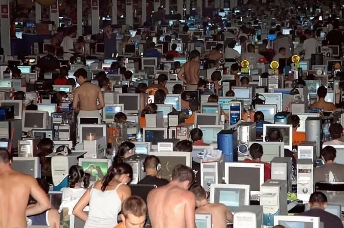 Crowded room of people at computer screens in a bizarre, unconventional setting.