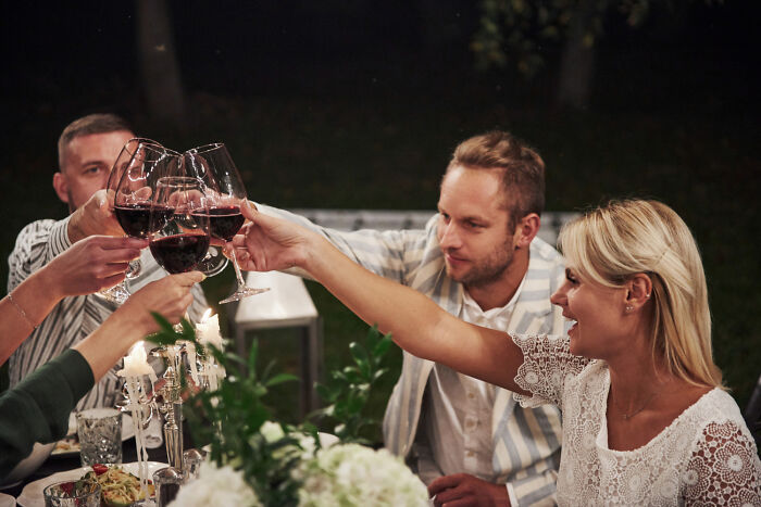 People enjoying a toast at a candlelit dinner, symbolizing rules made for one individual.