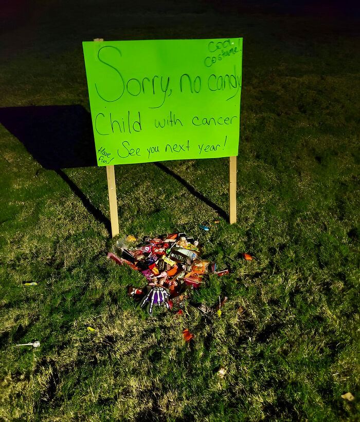 Sign with uplifting message next to a pile of candy on grass, spreading positivity and kindness.