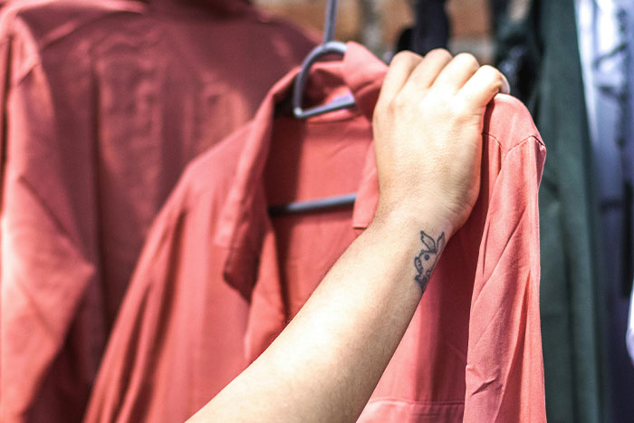 A hand holding a pink shirt on a rack, exploring fashion side hustle ideas.
