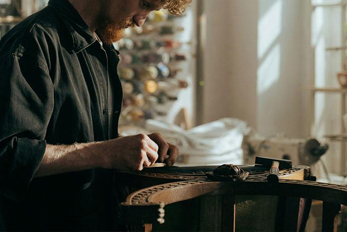 Man working on a woodworking project in a sunlit workshop, surrounded by tools and materials.