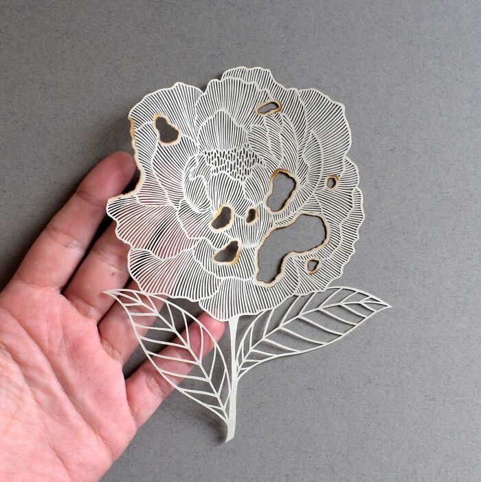Intricate paper art design of a flower in a hand, showcasing nature-inspired details.