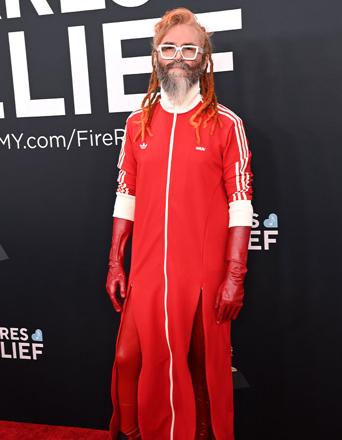 Person in red outfit with gloves and white glasses at the 2025 Grammys red carpet disaster event.