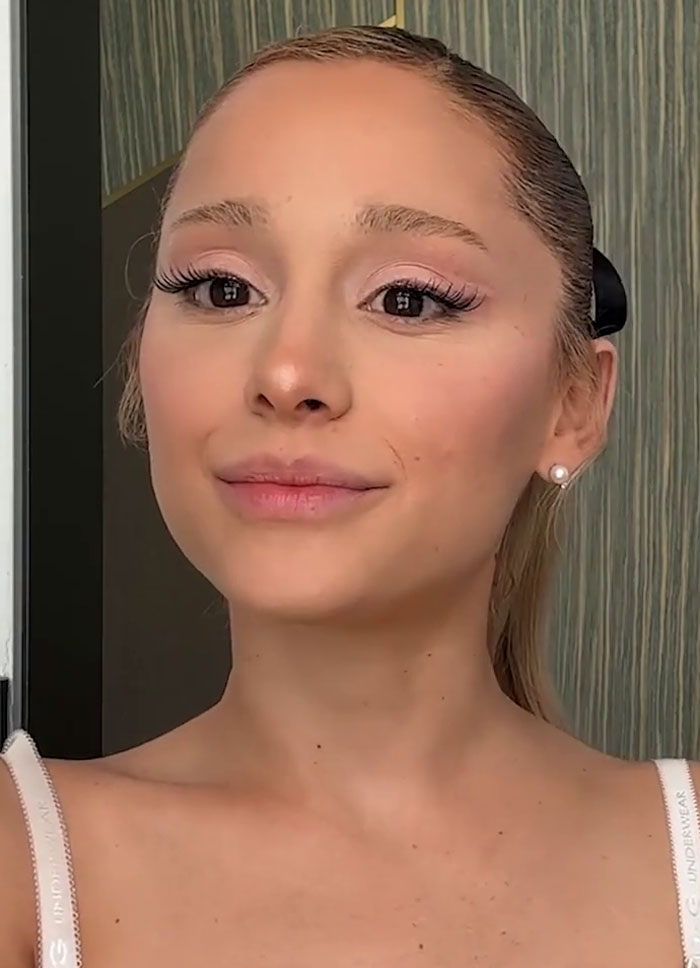 Person with long hair, wearing earrings, posing for a photo.
