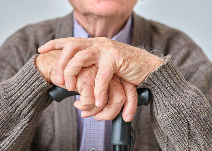 Elderly man’s hands resting on a cane, symbolizing the heartfelt and chilling moments of dying patients' last words.