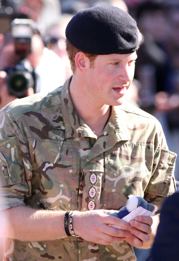 Man in military uniform and beret, holding an item, with people and cameras in the background, related to celebrity insight.