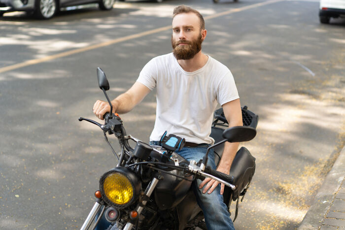 Man with a beard sitting on a motorcycle in the street, related to common USA things that confuse foreigners.