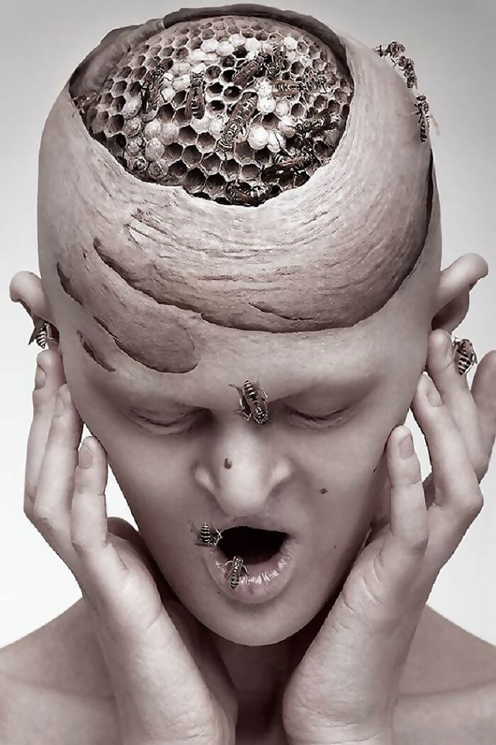 Unique model with surreal bee hive concept on head, expressing astonishment.