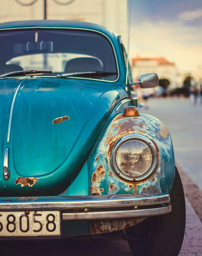 Old car with rust spots, considered trashy when poor but trendy among the rich for vintage appeal.