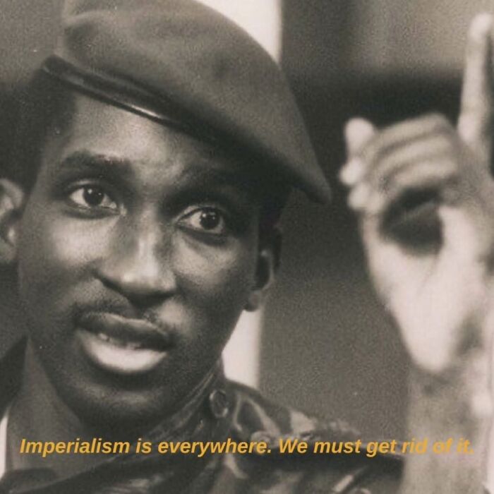A person in a uniform with a caption on anti-capitalism, expressing a message against imperialism.