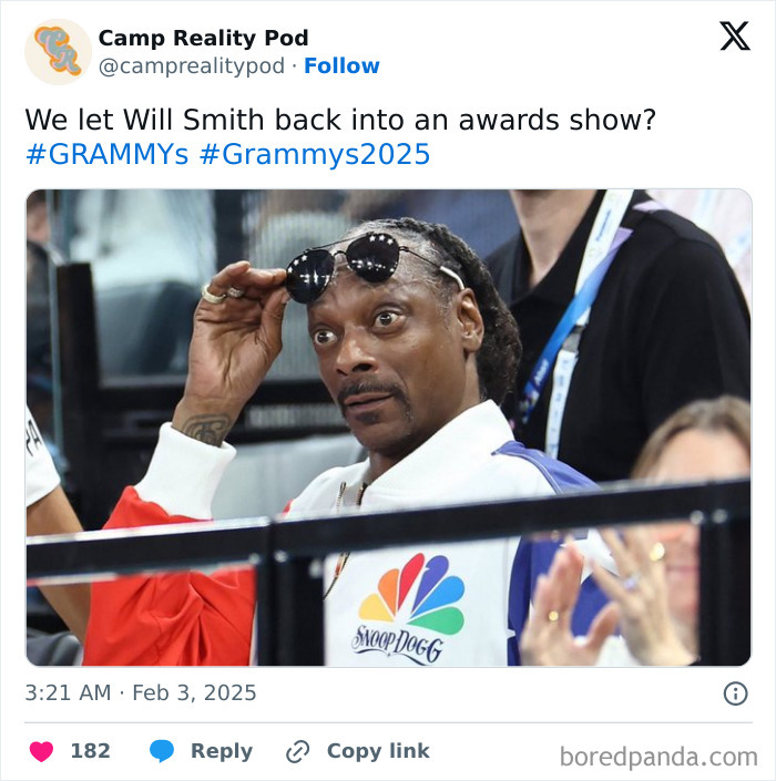 Man in a colorful jacket attending the 2025 Grammys, lifting his sunglasses in surprise.