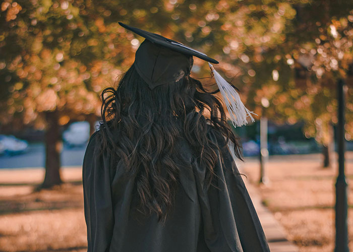 Person in graduation attire walking outdoors, symbolizing new beginnings and triumph over bosses.