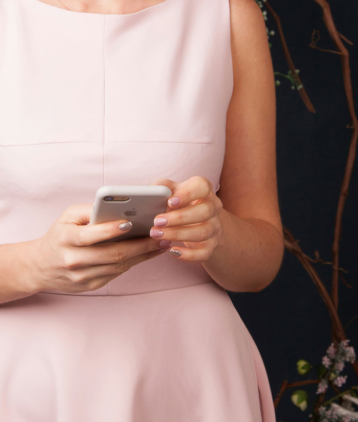 Woman in a pink dress holding a smartphone, possibly looking into a man's background.