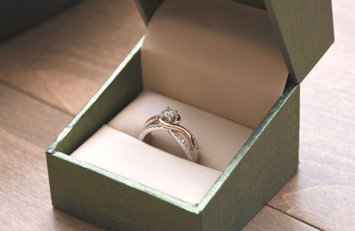 Elegant diamond ring in an open box, highlighting the concept of classy versus trashy based on wealth perception.
