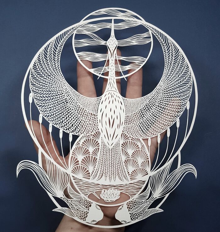 Intricate paper art design by Pippa Dyrlaga, showcasing a detailed, nature-inspired piece held against a dark background.